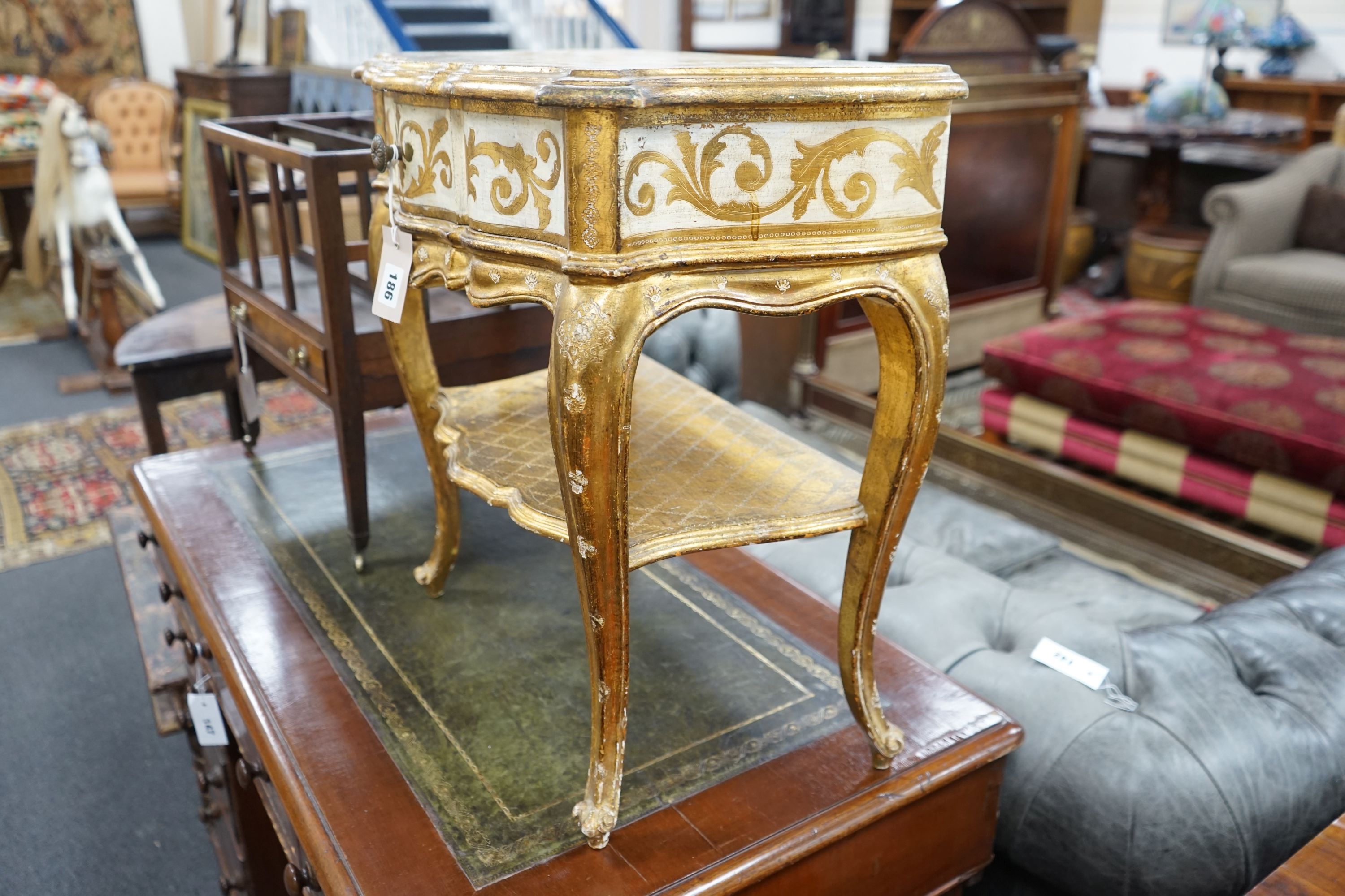 A Florentine gilt and cream painted serpentine two tier side table, width 50cm, depth 34cm, height 58cm